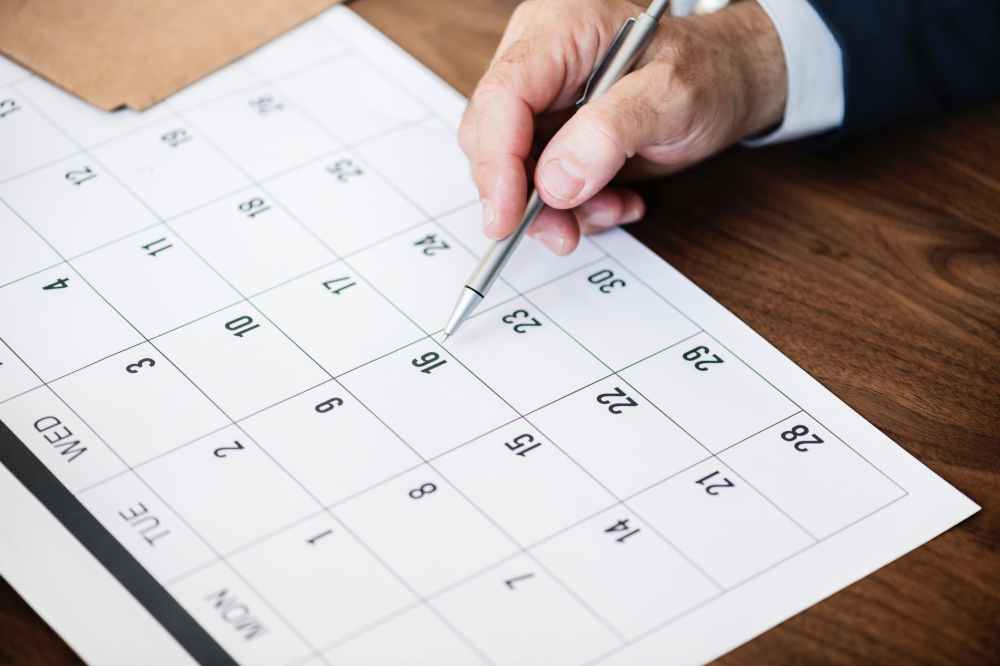 person pinpointing pen on calendar